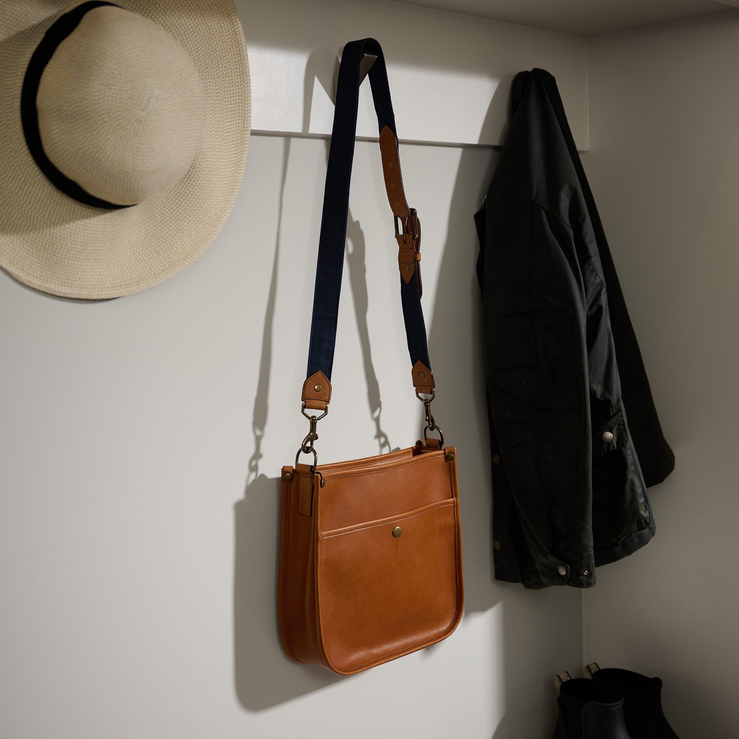 full grain leather purse crossbody bag for women hanging on coat rack - saddle tan leather