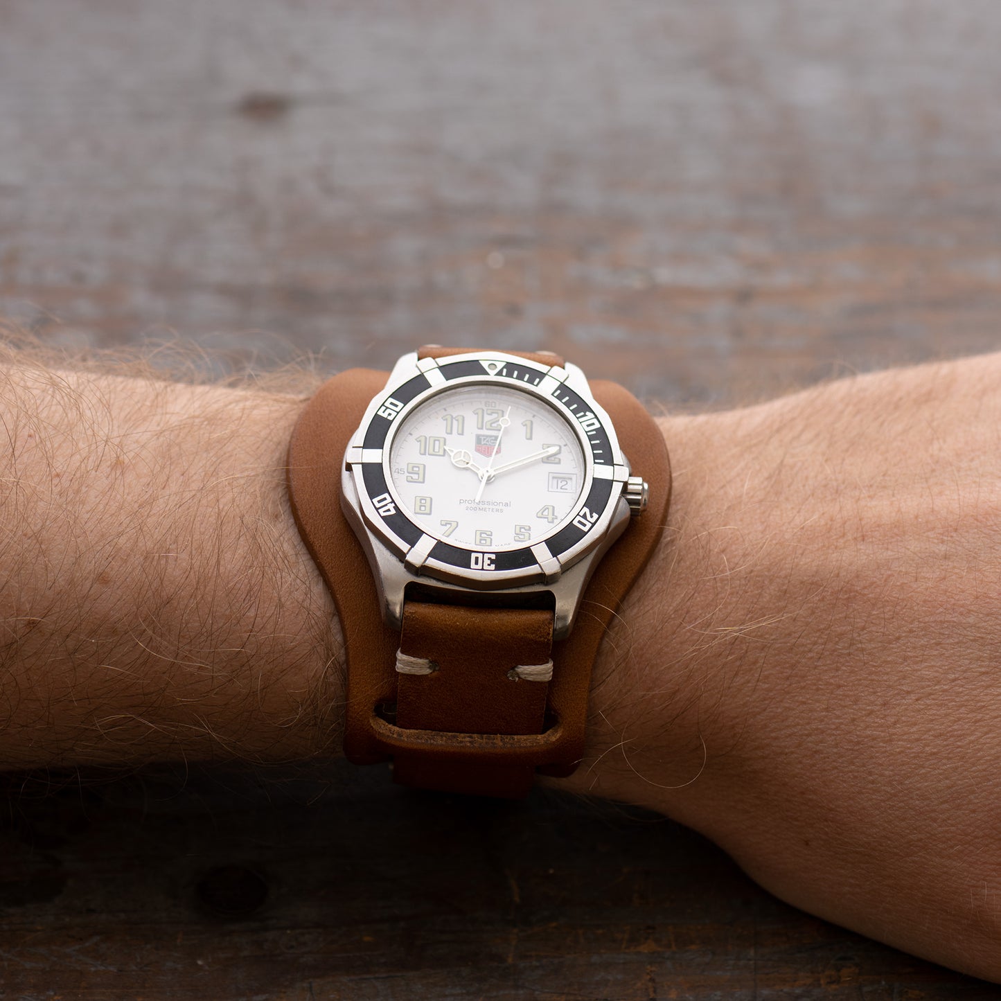 full grain Italian vegetable tanned leather watch strap with bund pad on wrist with white watch in saddle tan color